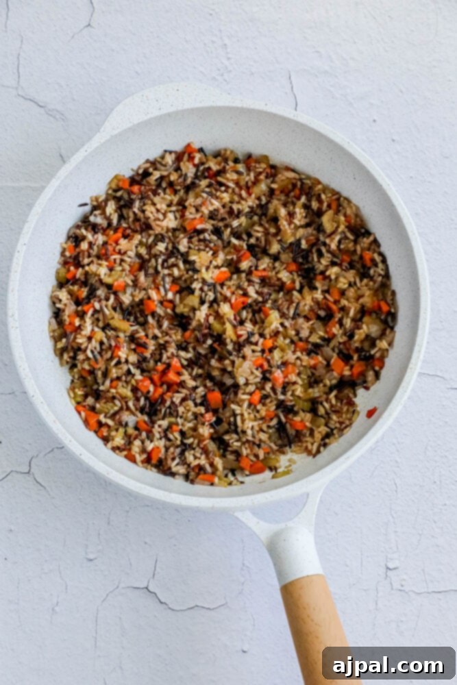 A vibrant display of sautéed wild rice pilaf in a pan, capturing the rich colors and textures of the grains and mixed vegetables, highlighting the culinary process.