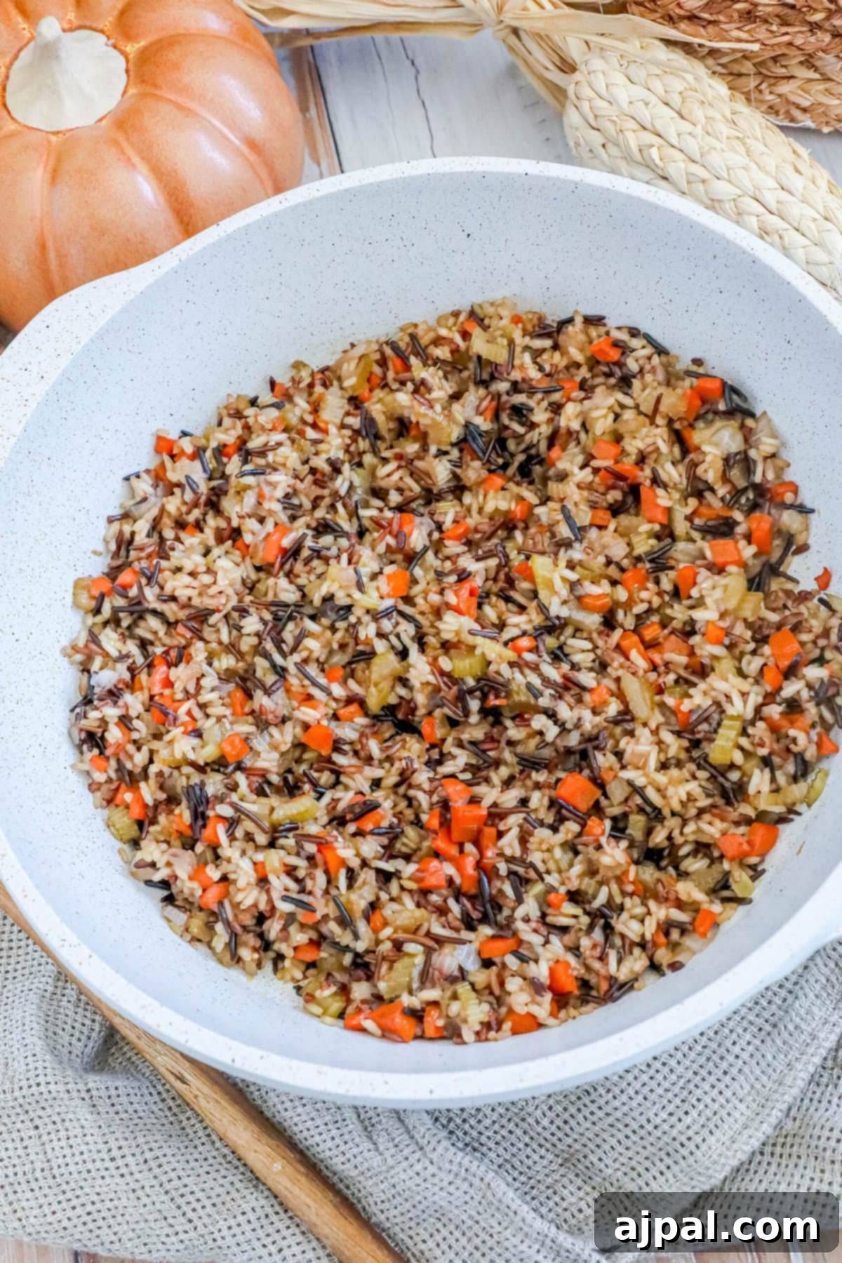 A stunning overhead view of wild rice pilaf in a white pan, adorned with fresh herbs, elegantly placed on a rustic table with a wooden spoon nearby, inviting you to indulge.
