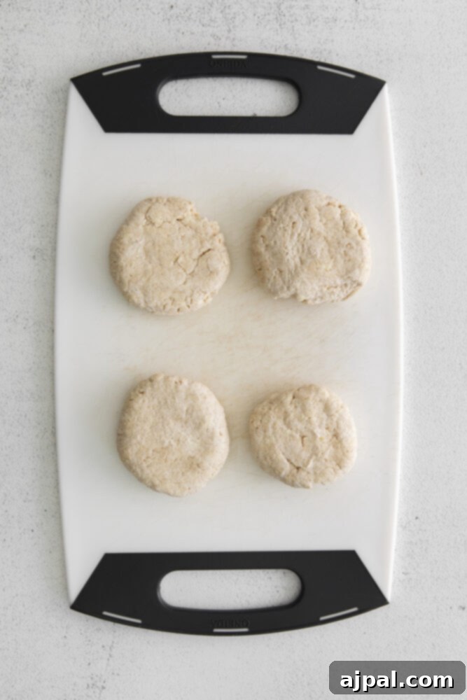 Four beautifully shaped apple galette tarts arranged on a cutting board, ready for the oven.