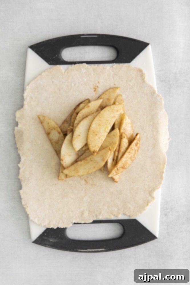 Thinly sliced apples, ready for the galette filling, on a wooden cutting board.