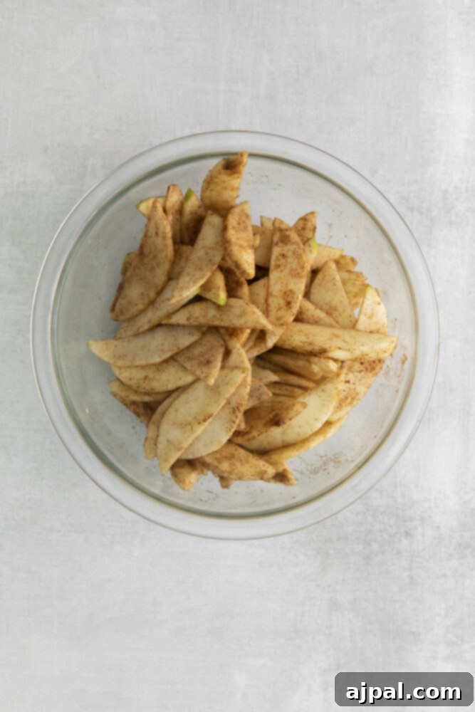 A bowl of apple slices ready for seasoning, a key step for a delicious galette filling.