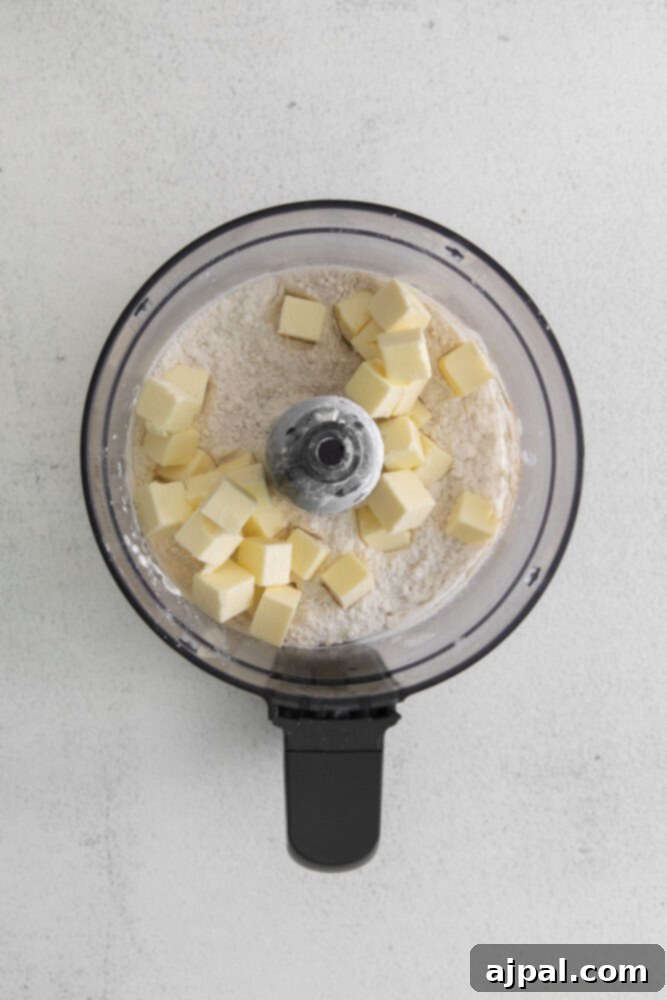 The dough coming together in a food processor, forming a crumbly texture ideal for galettes.