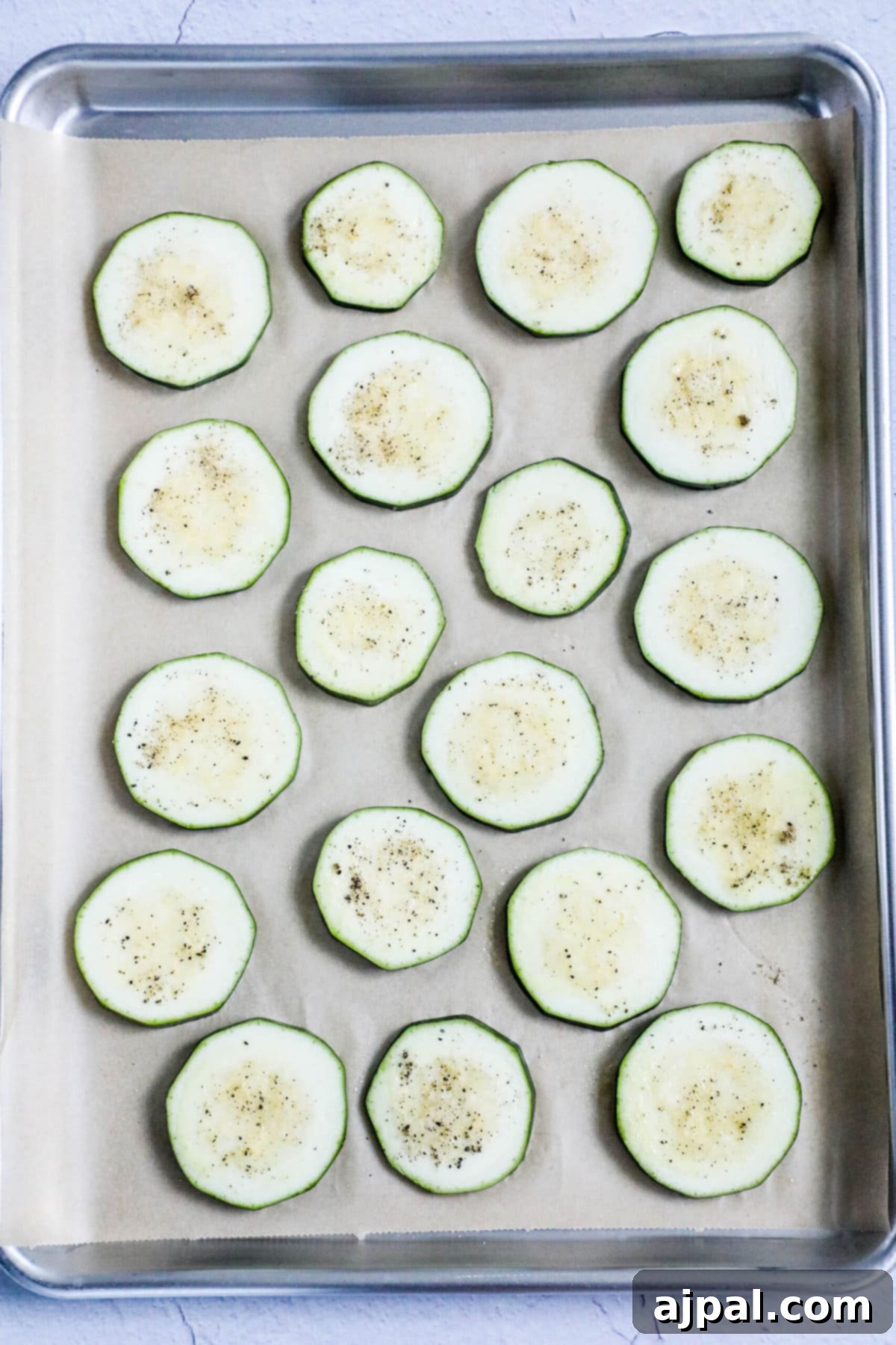 Parmesan Crusted Zucchini 6 picture of sliced zucchini with seasonings on a baking sheet lined with parchment paper