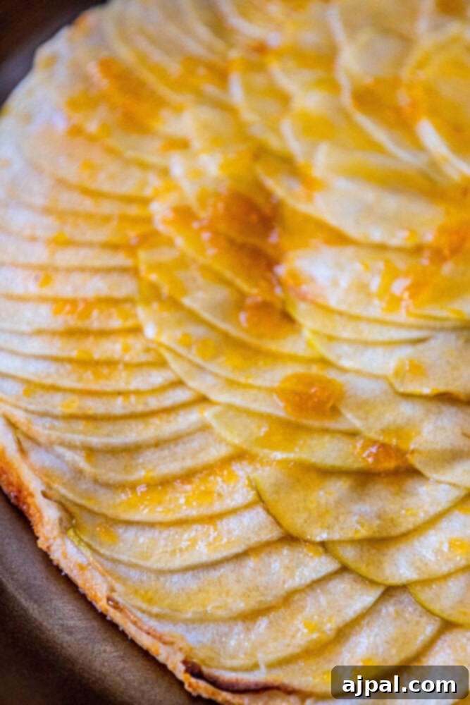Simple Perfection: French Apple Tart 4 A perfect slice of French apple tart, revealing layers of soft apple and flaky pastry, served on a plate.