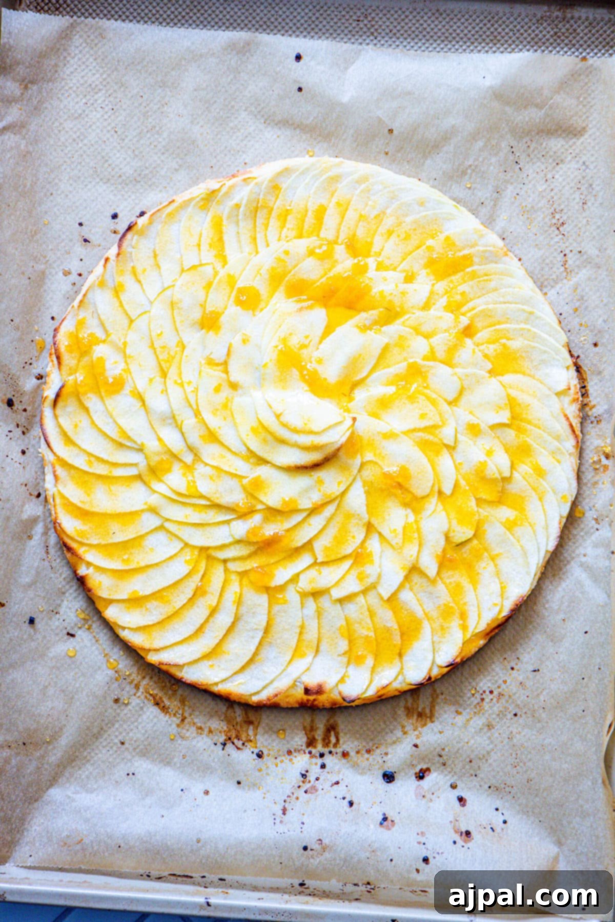 Simple Perfection: French Apple Tart 9 An unbaked French Apple Tart, beautifully arranged with apple slices, generously drizzled with apricot jam, and dotted with cubes of butter, ready for the oven.