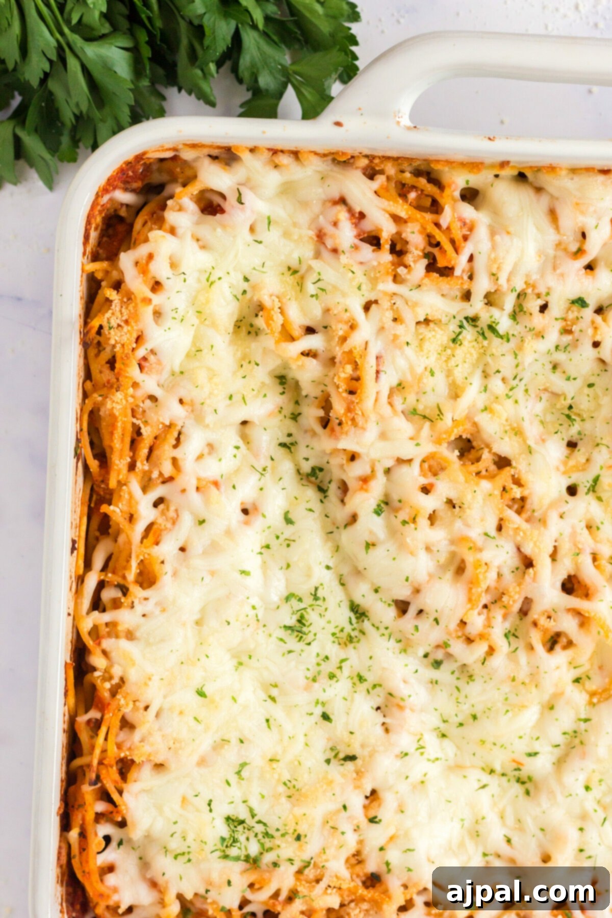 Ultimate Cheesy Spaghetti Bake 9 picture of baked spaghetti with melted cheese in a white casserole dish