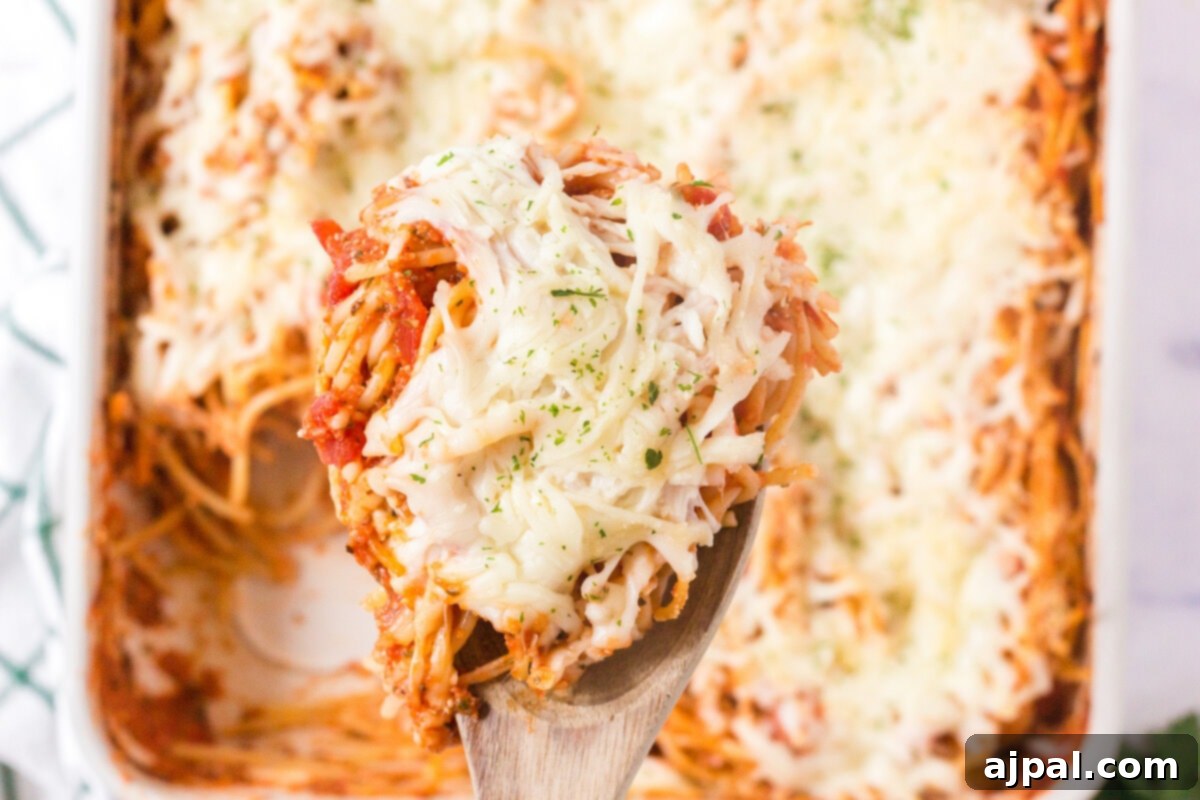 Ultimate Cheesy Spaghetti Bake 10 picture of baked spaghetti on a spoon with melted cheese