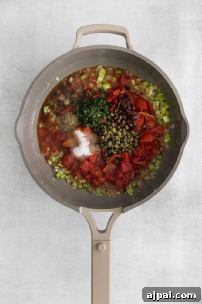 No-Fuss Eggplant Caponata 8 Diced tomatoes are added to a pan, joining the already browned peppers, onions, and fragrant herbs, creating a rich base for the caponata sauce.