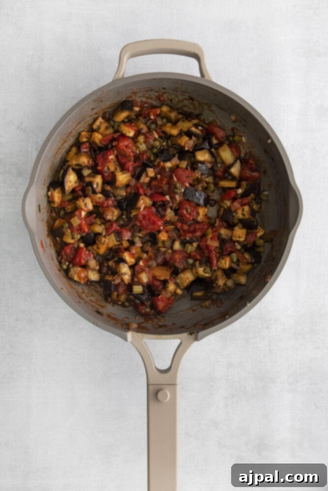 No-Fuss Eggplant Caponata 10 A close-up of the finished eggplant caponata, rich and thick, bubbling gently in the pan, showcasing its deep colors and inviting texture.