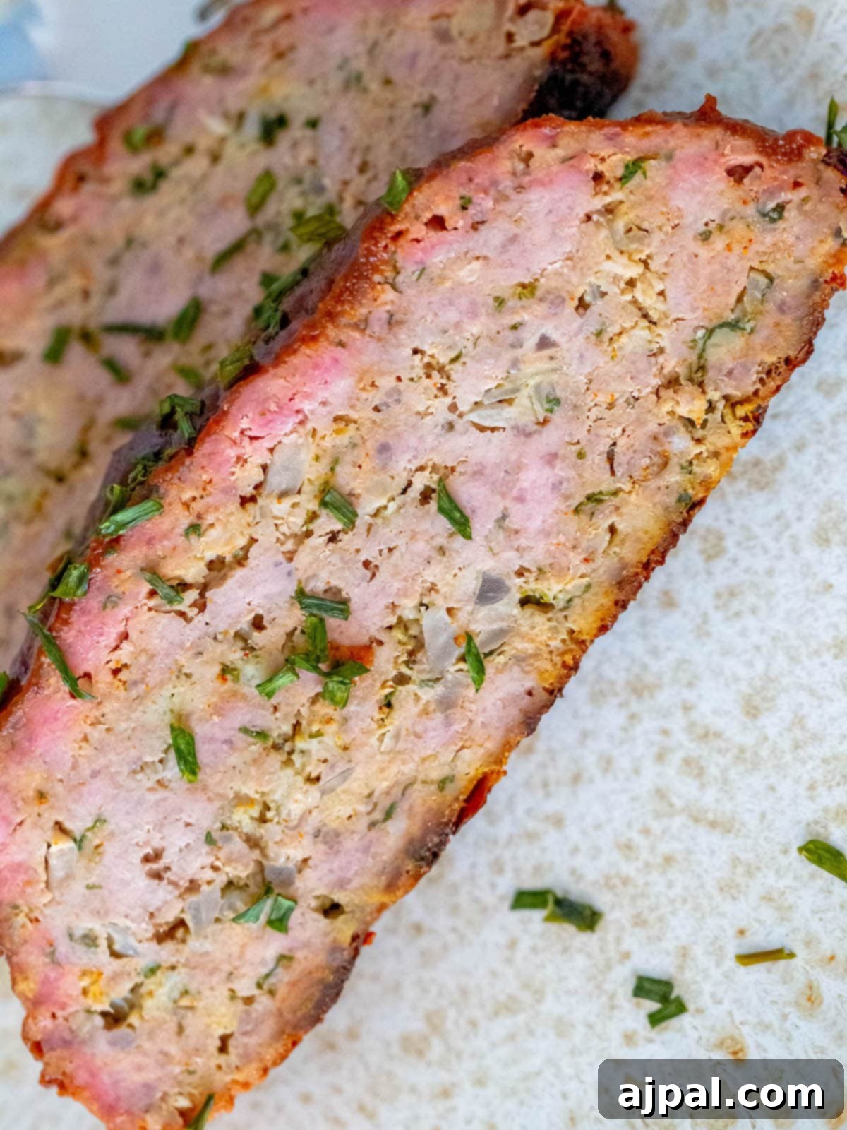 A close-up slice of smoked meatloaf, revealing its moist texture and savory composition.