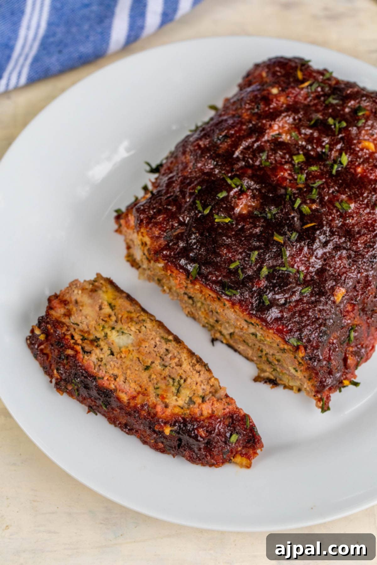 Smoked meatloaf on a white plate with one slice cut out, ready to be enjoyed.
