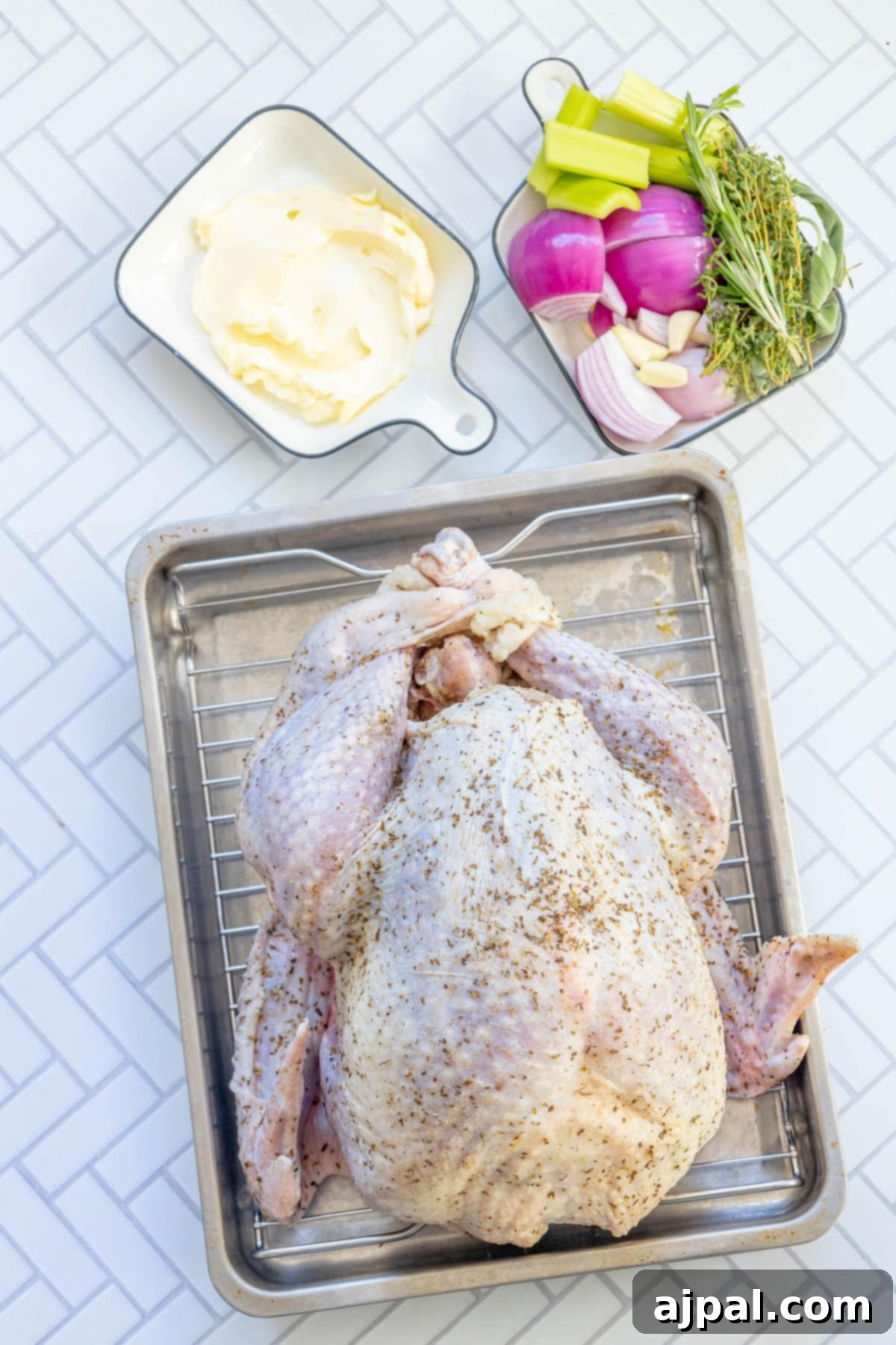 picture of brined turkey next to butter, herbs, chopped onion, softened butter on a table