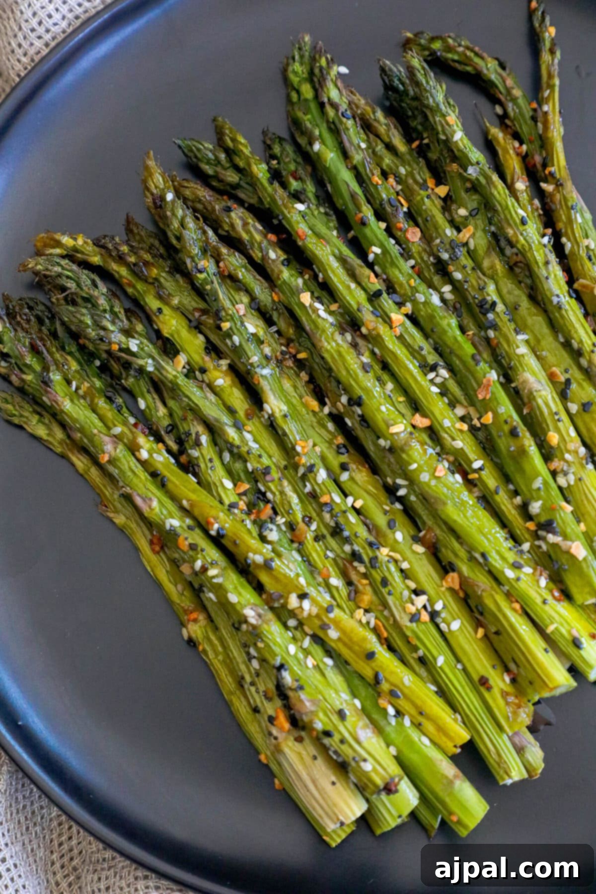 Plate of perfectly roasted everything bagel seasoned asparagus with sesame seeds.