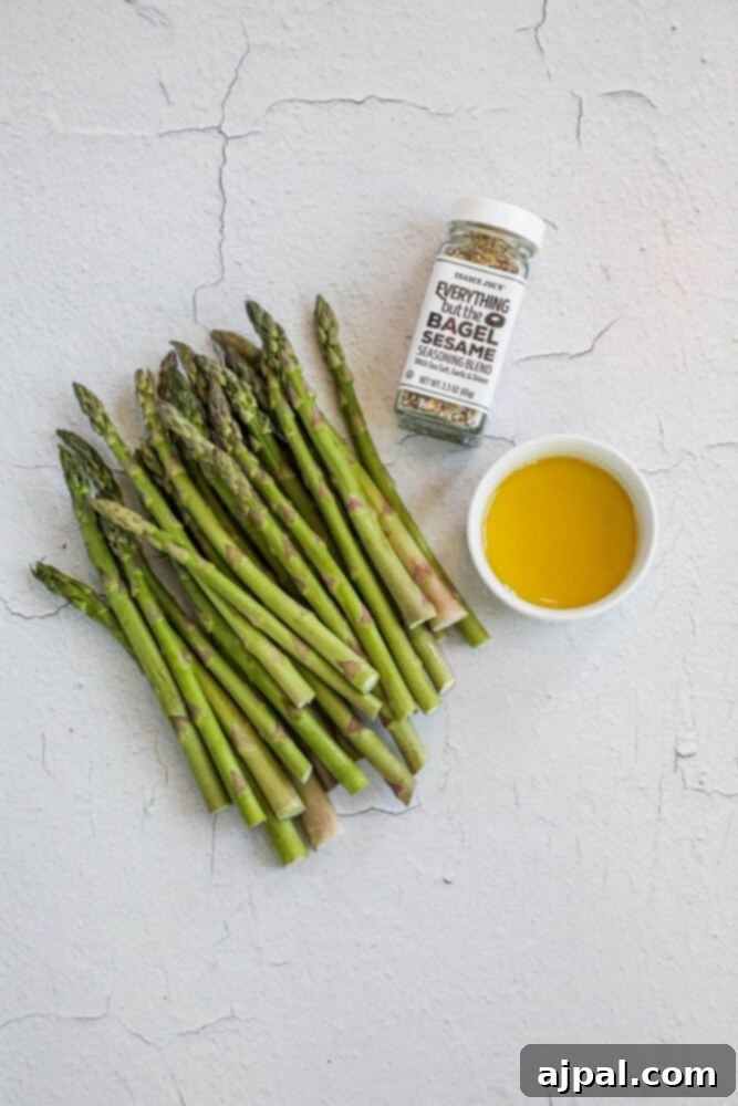 Ingredients laid out for everything bagel seasoned asparagus: fresh asparagus, olive oil, everything bagel seasoning, and sea salt.