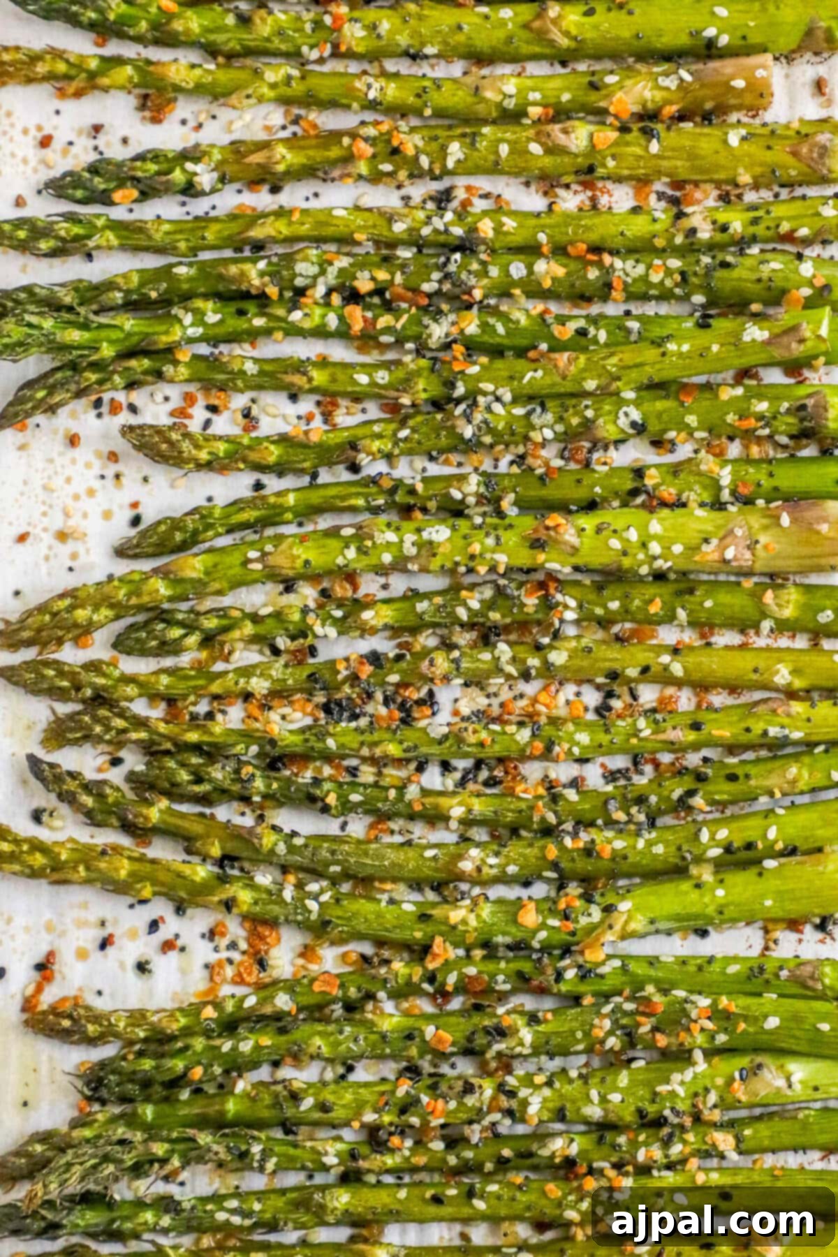 Roasted asparagus with everything bagel seasoning on a baking sheet, fresh out of the oven.
