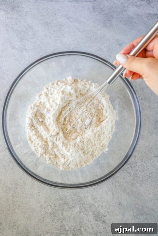Chewy Funfetti Cookie Bars 6 A hand mixing flour in a glass bowl to prepare delicious jumbo funfetti cookies.