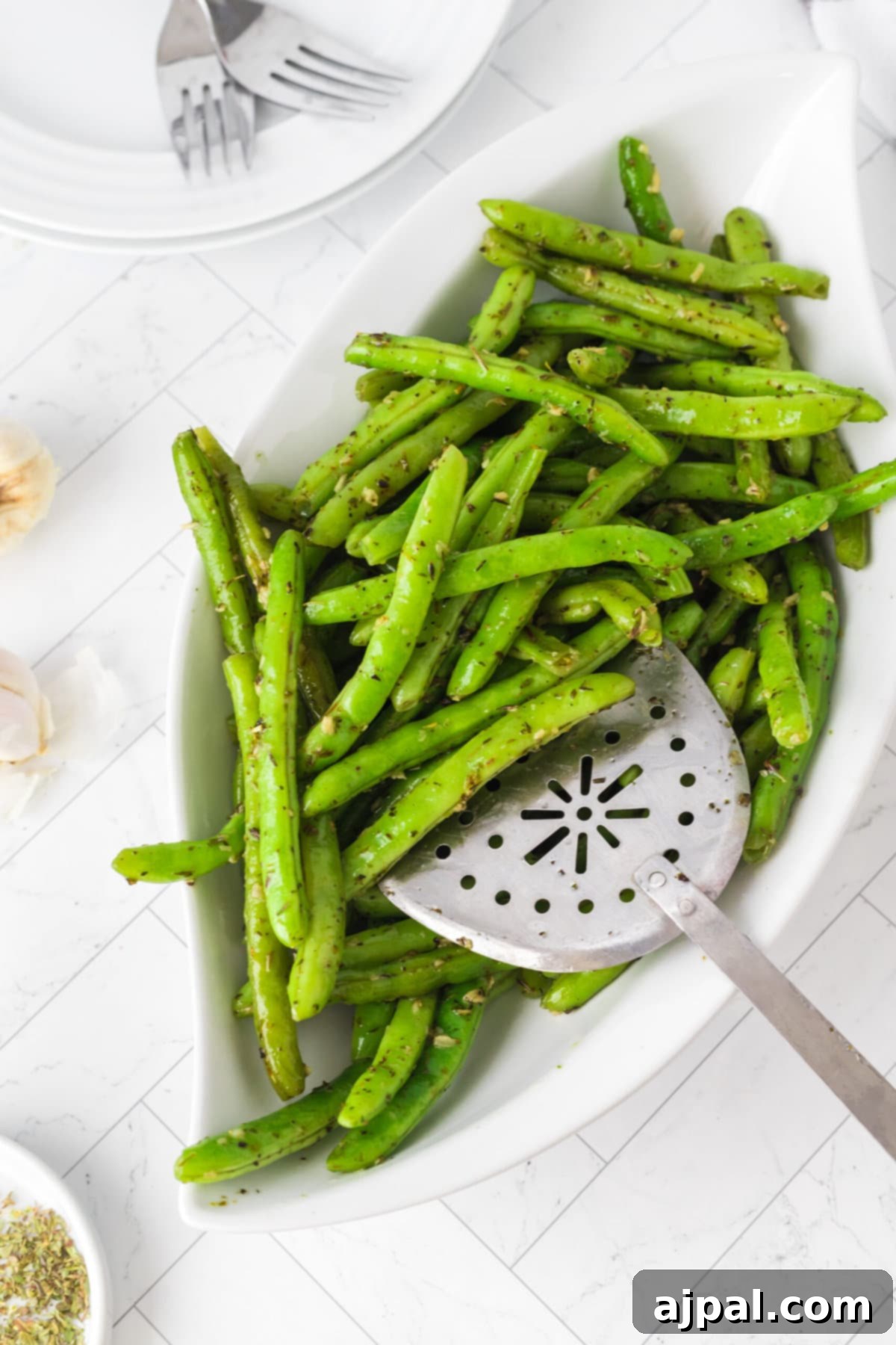 Garlic Herb Green Beans served in a white bowl, seasoned beautifully with herbs and minced garlic.