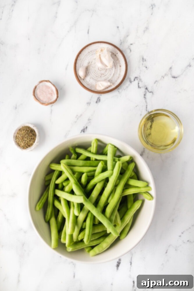 Uncooked green beans and minced garlic ready for sautéing on a marble surface.