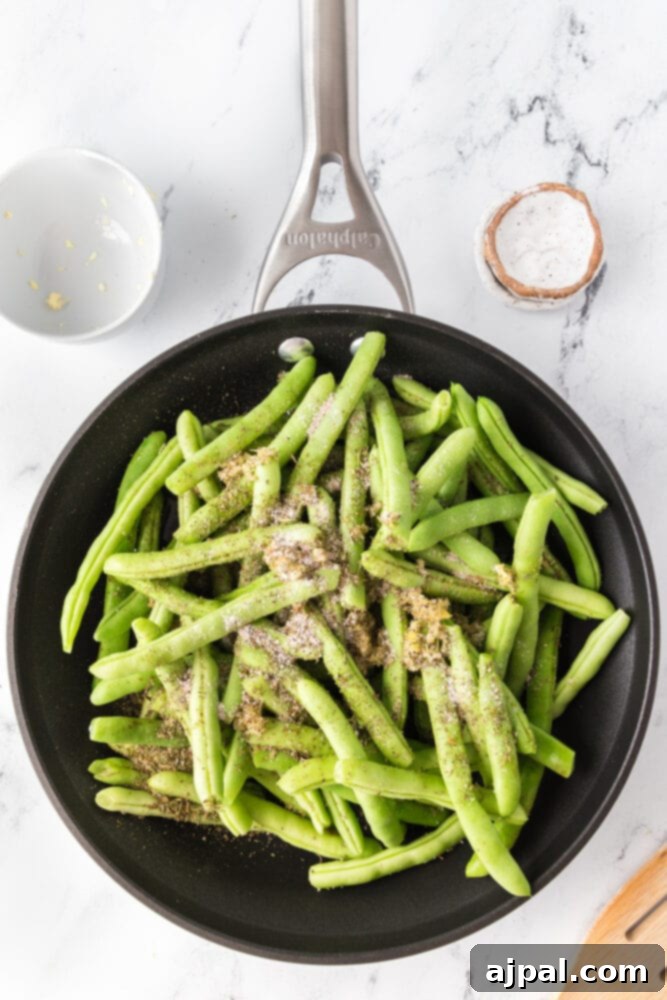 Garlic herb green beans being cooked in a frying pan, showing their vibrant color.