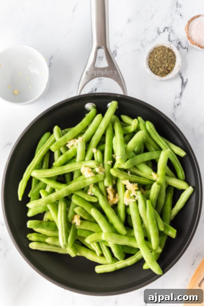 Sautéed green beans with garlic and herbs simmering in a skillet, steam rising.
