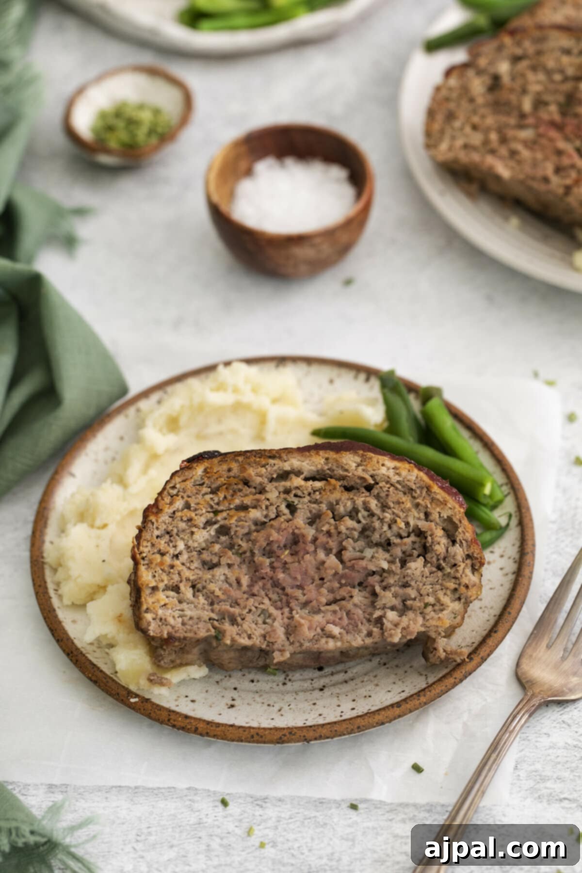 meatloaf on a plate with potatoes and green beans
