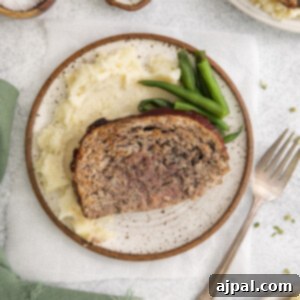 meatloaf on a white plate with mashed potatoes and green beans