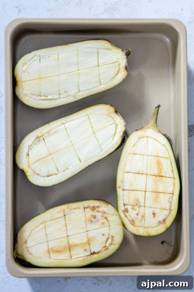 Vibrant Roasted Eggplant with Creamy Tahini and Pomegranate 6 picture of halved eggplants with a grid scored into them on a baking sheet