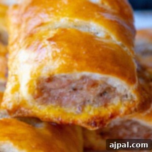 Classic English Sausage Rolls 14 Close-up picture of a single sausage roll in baked puff pastry, golden and flaky.
