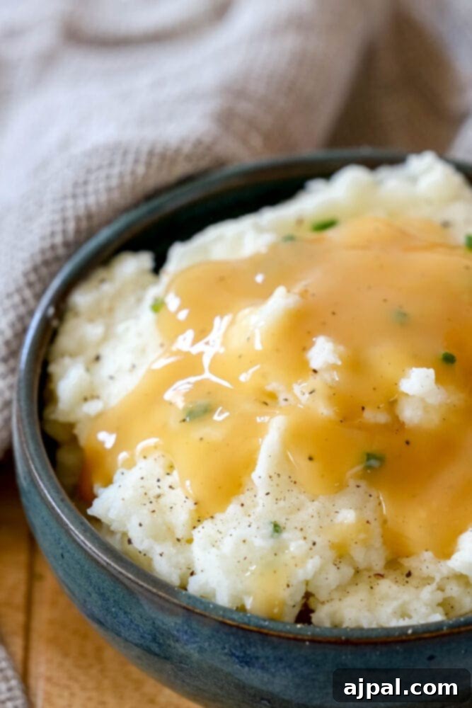 Creamy mashed potatoes in a serving bowl, generously topped with savory brown gravy.