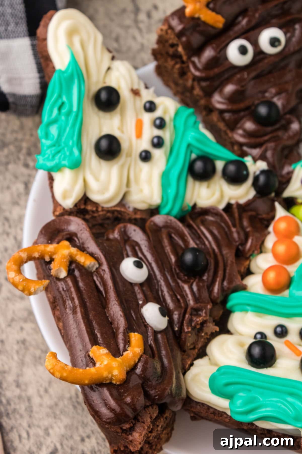 A beautifully arranged plate of frosted Christmas brownies, showcasing intricate icing designs and pretzel antlers, ready to be enjoyed.
