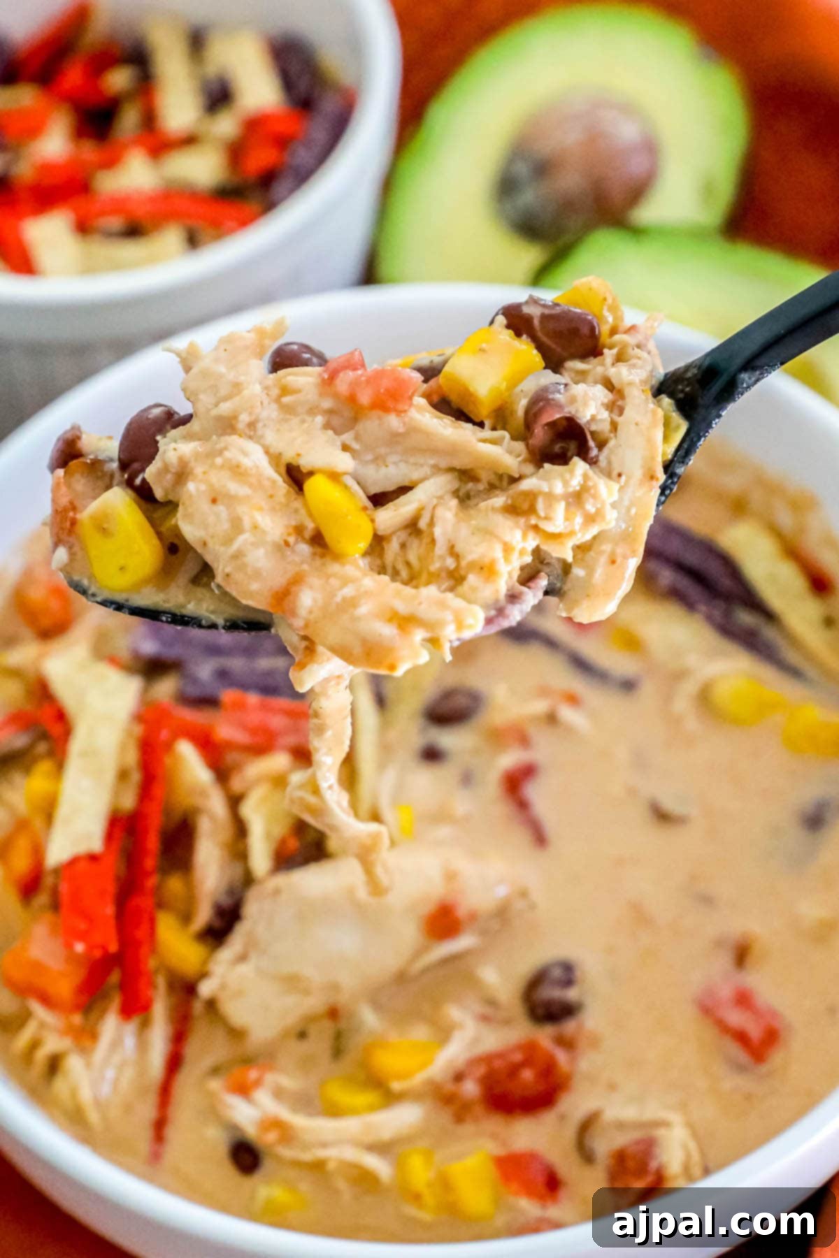 creamy chicken soup with beans, corn, rotel, and shredded chicken on a spoon