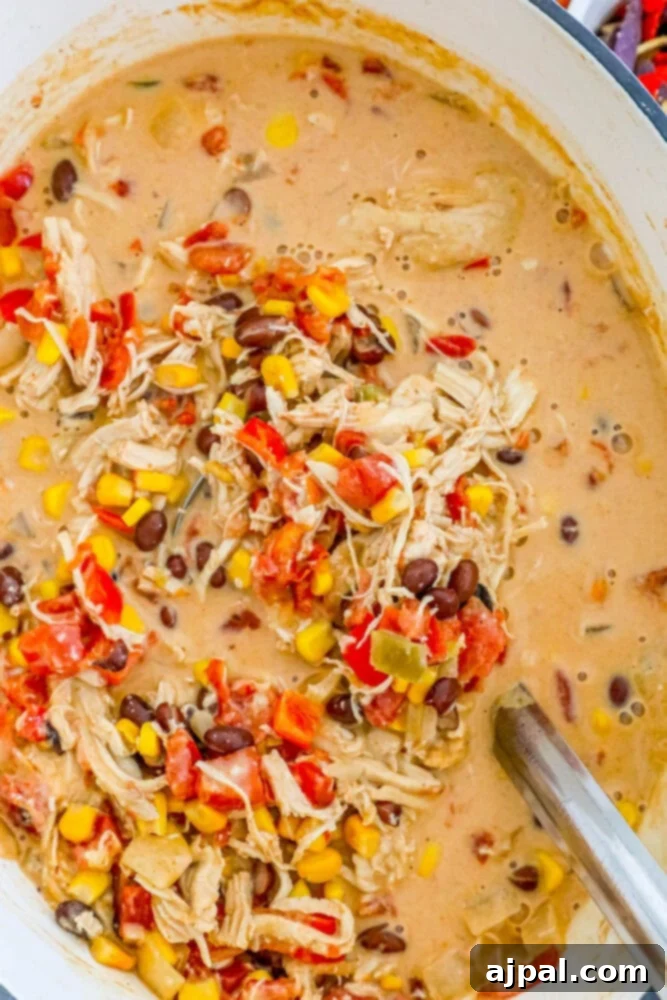 creamy taco soup in a pot with corn, tomatoes, beans, shredded chicken