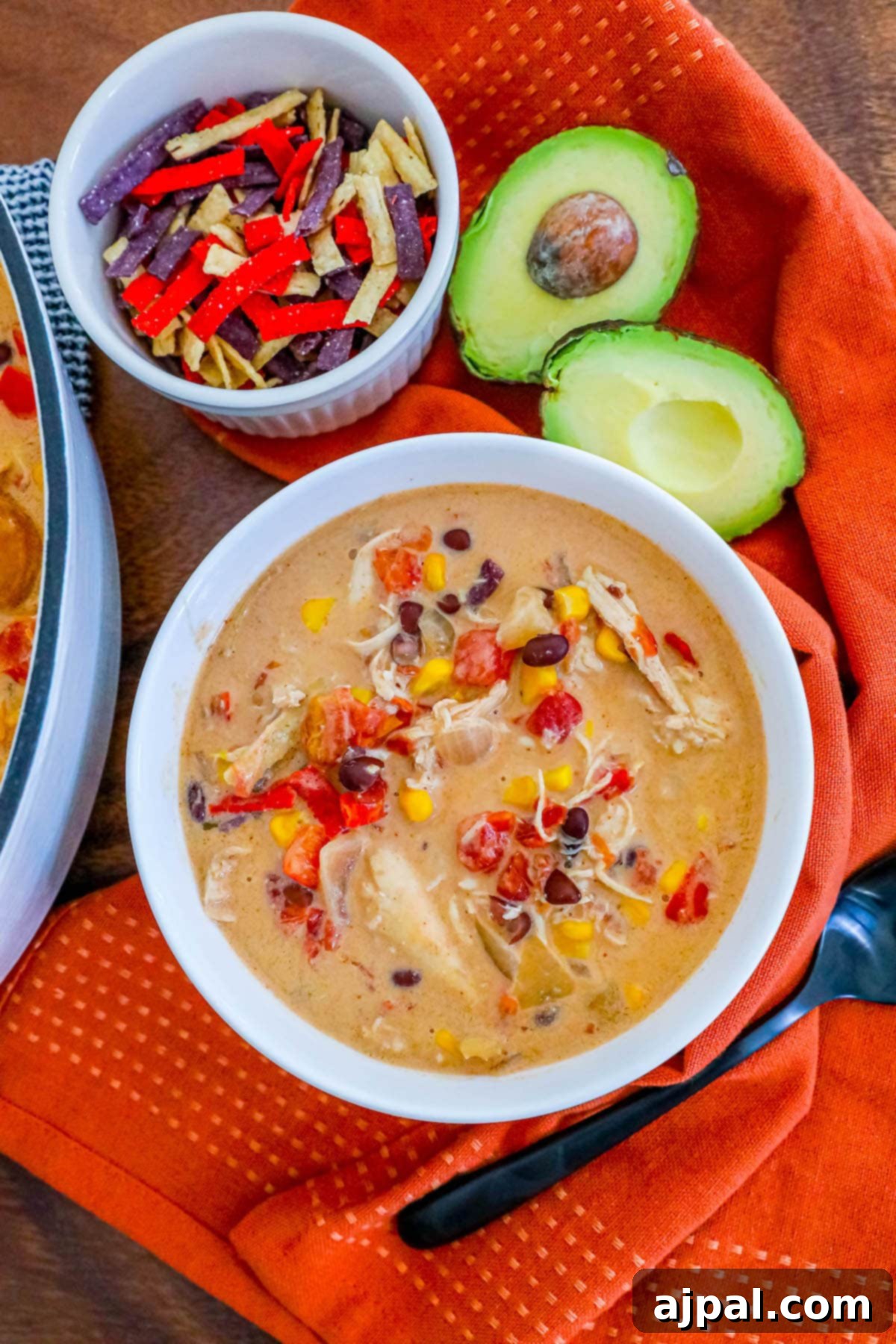 creamy chicken soup with beans, corn, rotel, and tortilla strips in a white bowl