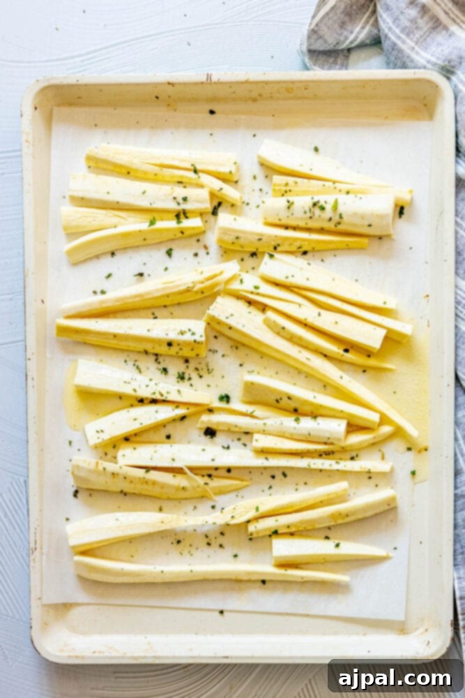 seasoned peeled and chopped parsnips on a baking sheet seasoned with herbs and garlic