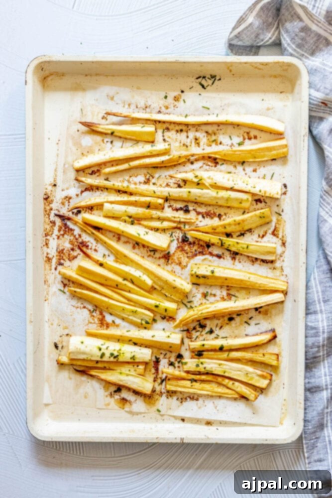 roasted parsnips on a baking sheet lined with parchment paper seasoned with garlic butter and herbs