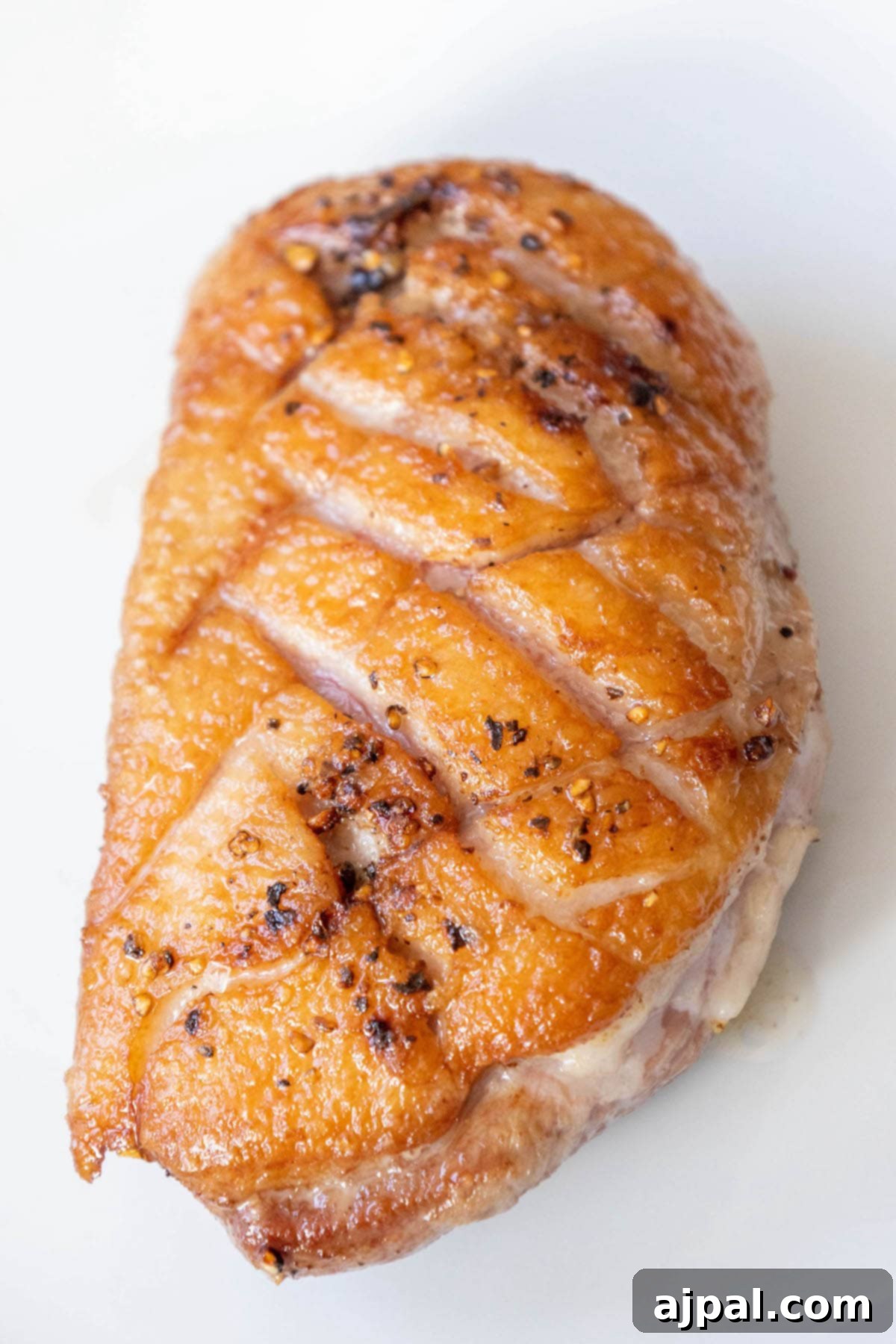 Golden-Crisp Duck Breast with Zesty Orange Reduction 7 Perfectly sliced duck breast with crispy fat seasoned with salt, pepper, and herbs, topped with a glistening orange sauce on a pristine white plate.