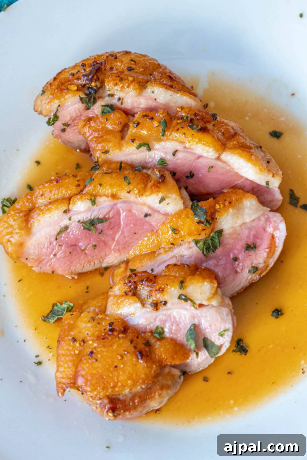 Golden-Crisp Duck Breast with Zesty Orange Reduction 8 A beautifully plated white plate featuring crispy seared duck breast in a vibrant orange sauce, garnished with fresh herbs, ready to be enjoyed.
