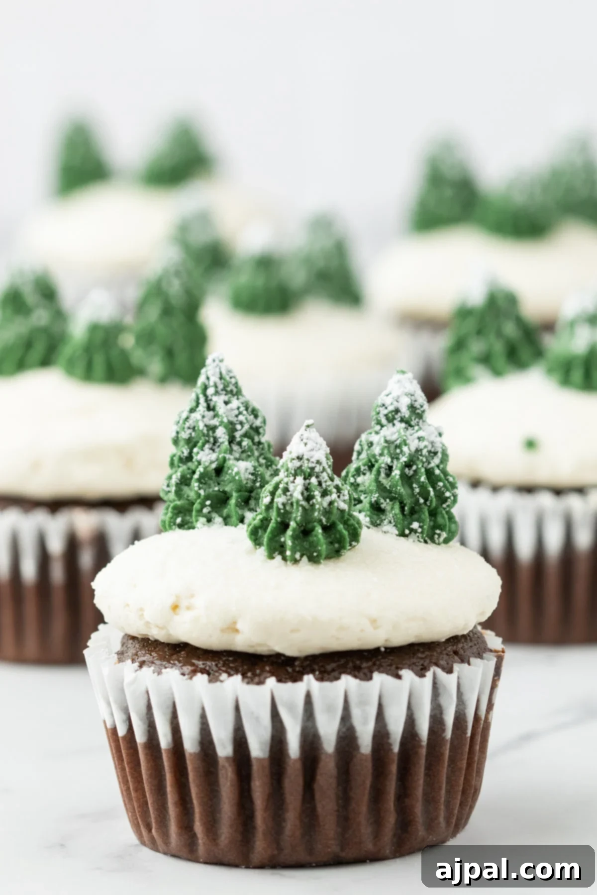 An enchanting mint chocolate cupcake, elegantly adorned with snowflakes, buttercream icing, and a dusting of powdered sugar snow, all nestled on a plate.