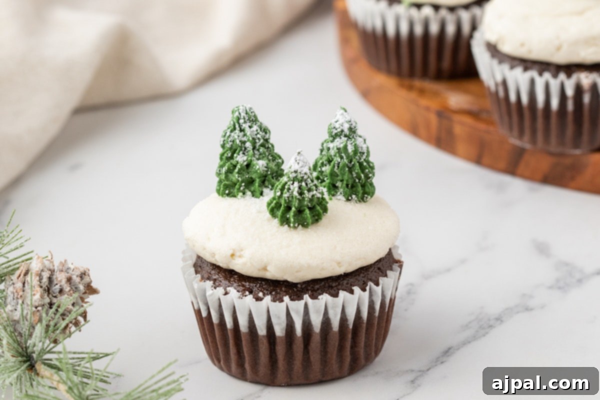 A festive array of mint chocolate cupcakes, beautifully decorated with delicate pine trees and tiny pine cones, arranged on a plate.