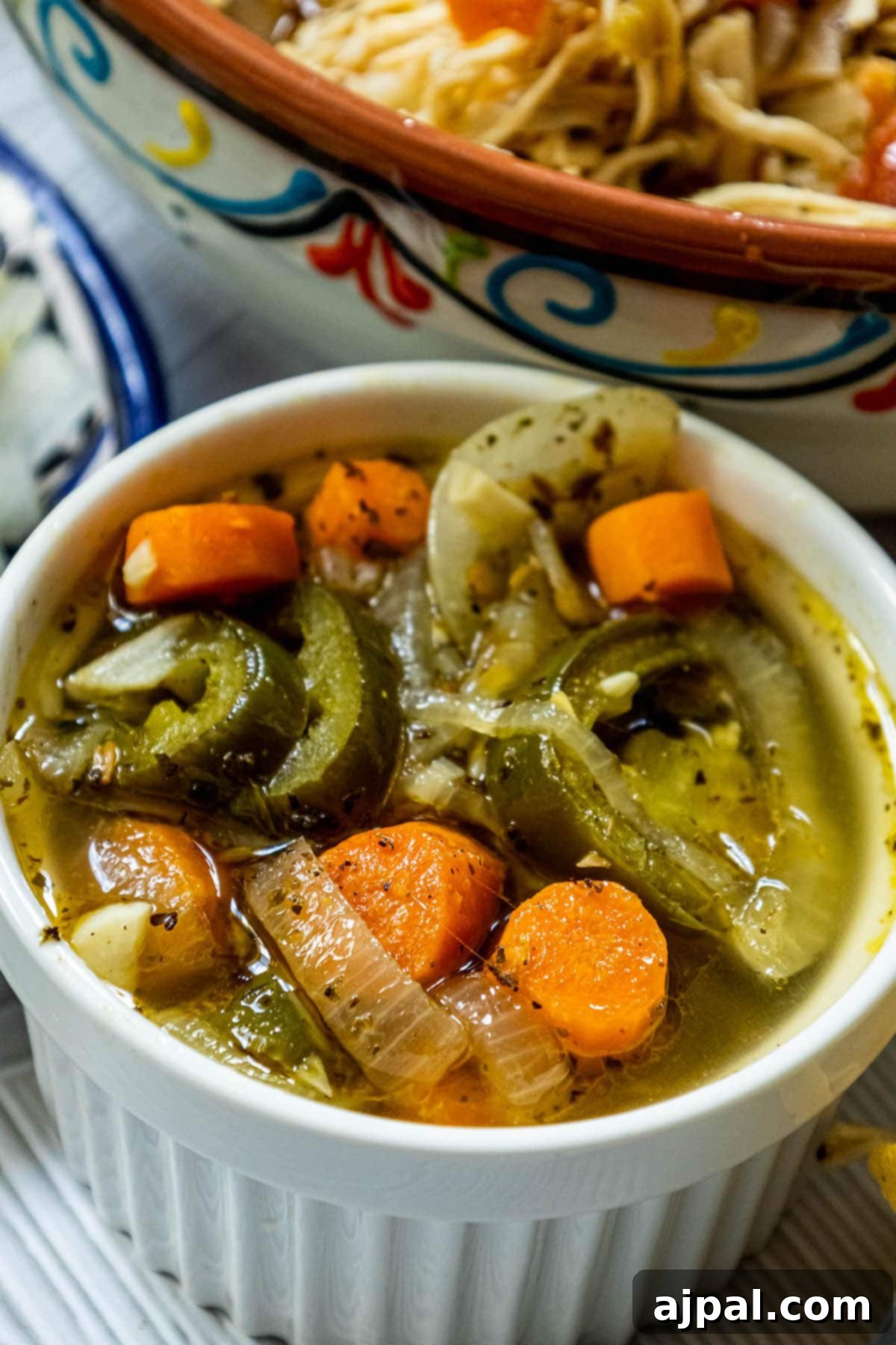 Zesty Carrot Jalapeno Relish 3 pickled jalapeños and carrots with onions, coriander, and pepper in a white dish