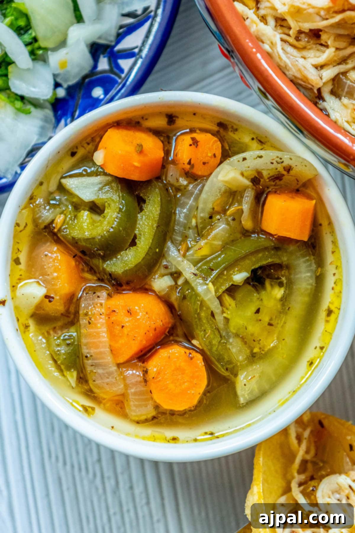 Zesty Carrot Jalapeno Relish 9 a white bowl with pickled carrots, jalapenos, and onions with spices in it