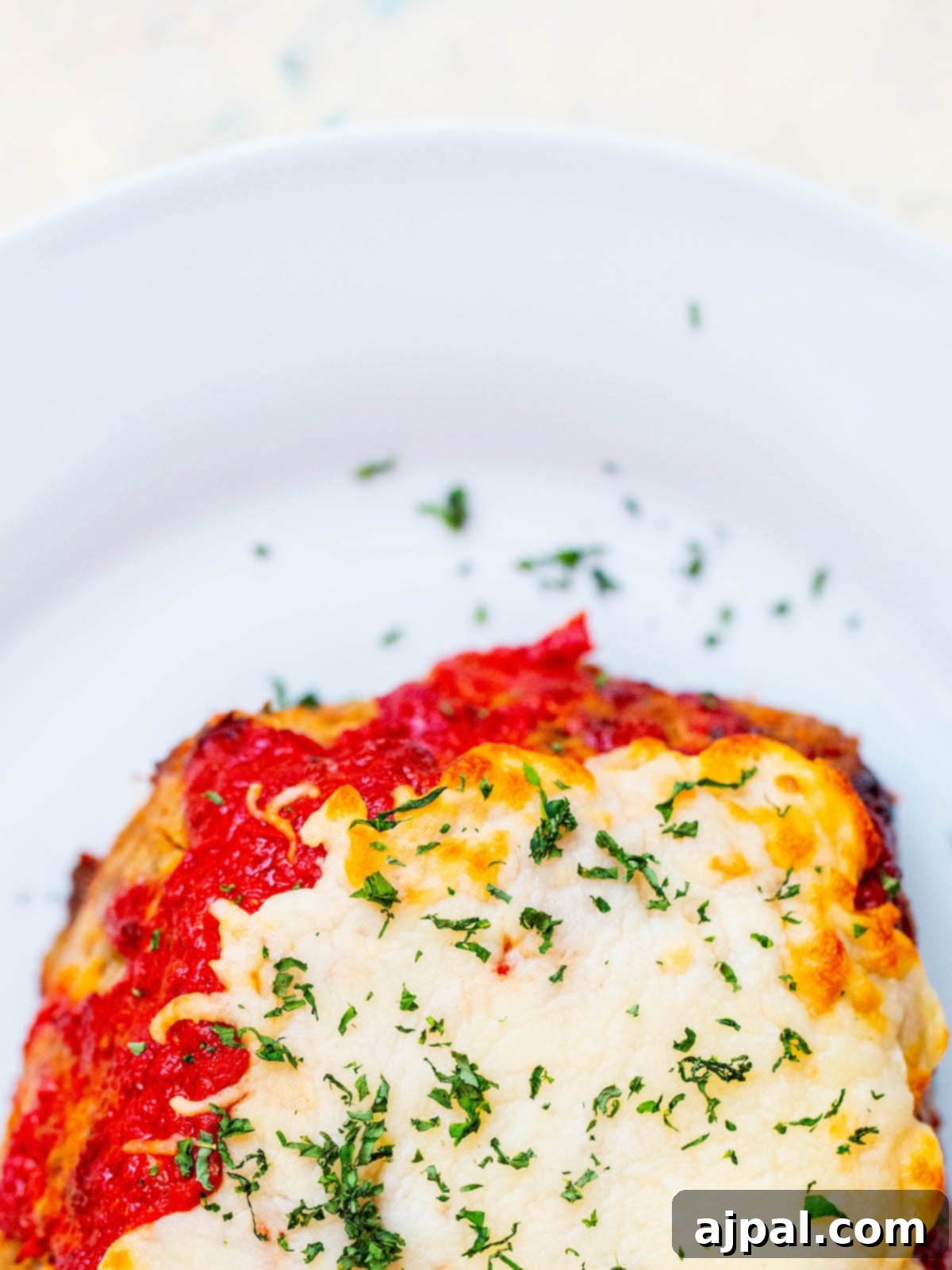 meatloaf covered in cheese on a white plate