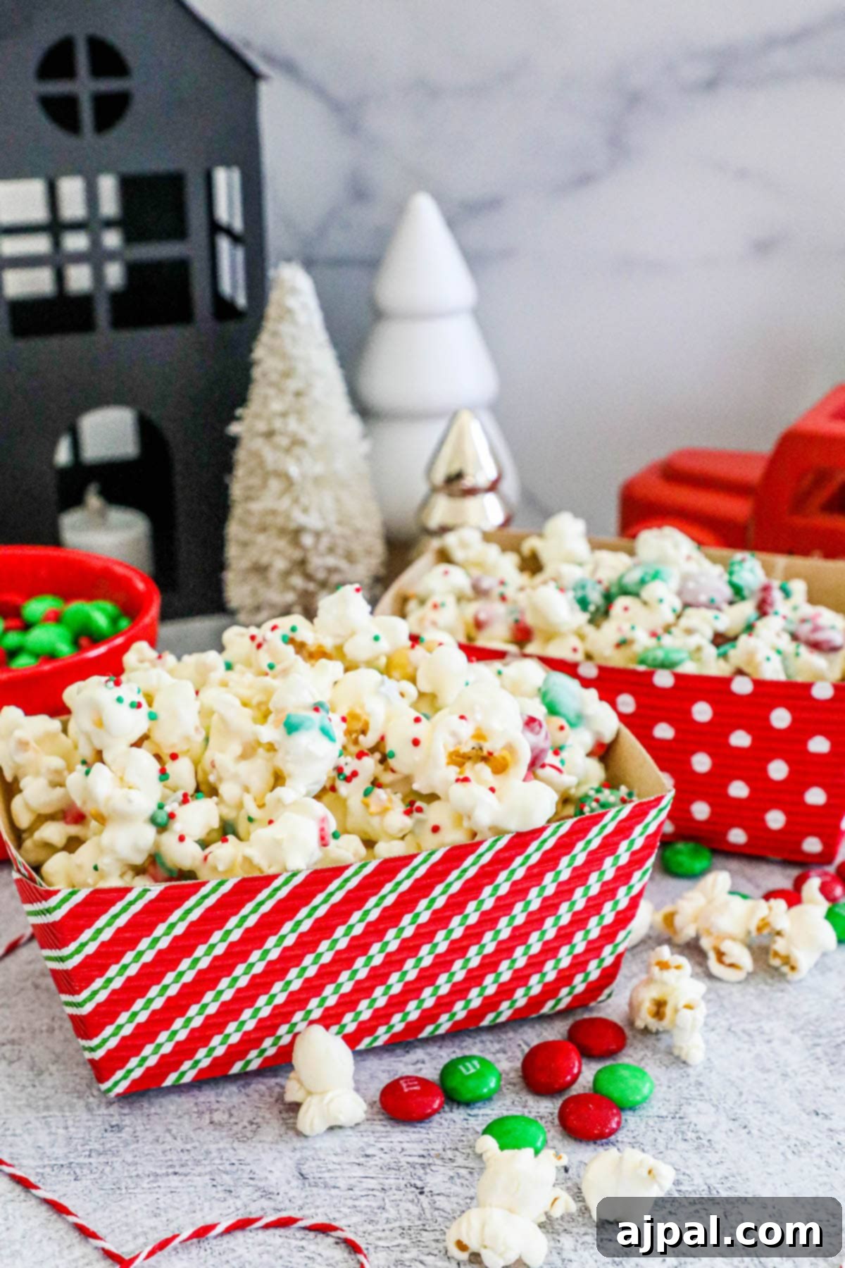 Festive reindeer popcorn in a striped box, brimming with candies and sprinkles on a cozy countertop.