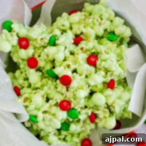 green candy coated popcorn with green and red christmas candies in a bowl on a table