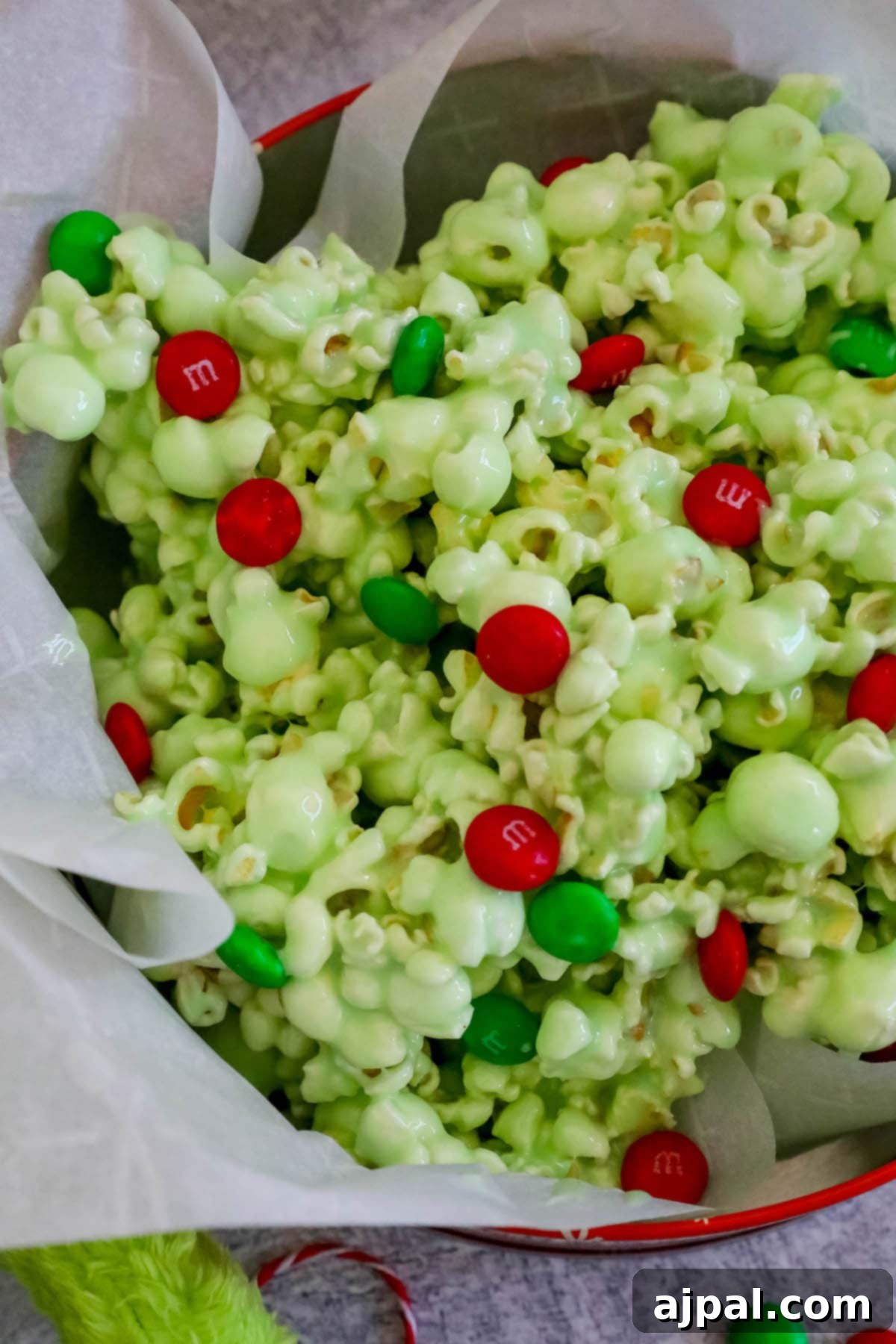 Grinch's Holiday Popcorn 3 candied christmas popcorn in a bowl with green and red m&ms