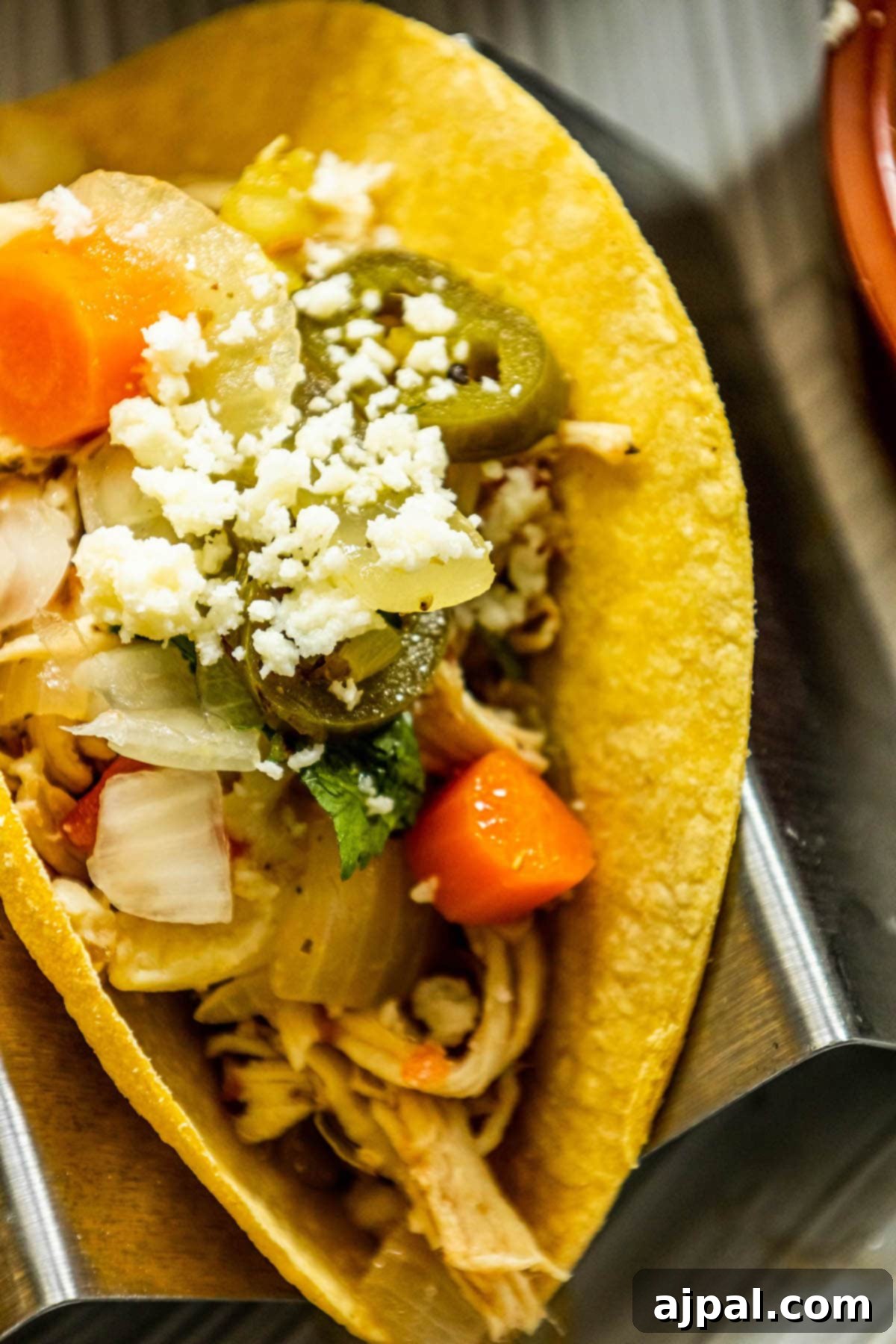 A plate of freshly prepared shredded chicken tacos, artfully adorned with a vibrant assortment of crisp vegetables and flavorful toppings, presenting a visually appealing and delicious meal.