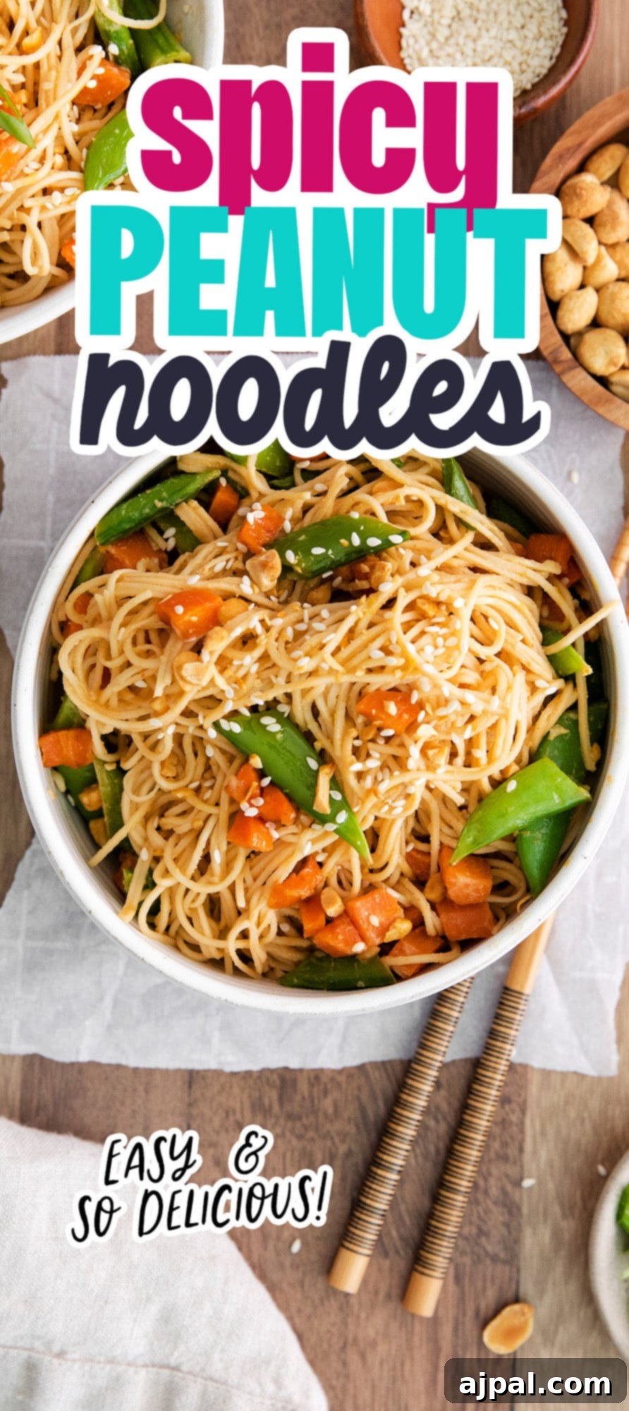 A beautifully plated bowl of spicy peanut noodles with peas and carrots, garnished with crushed peanuts and sesame seeds.