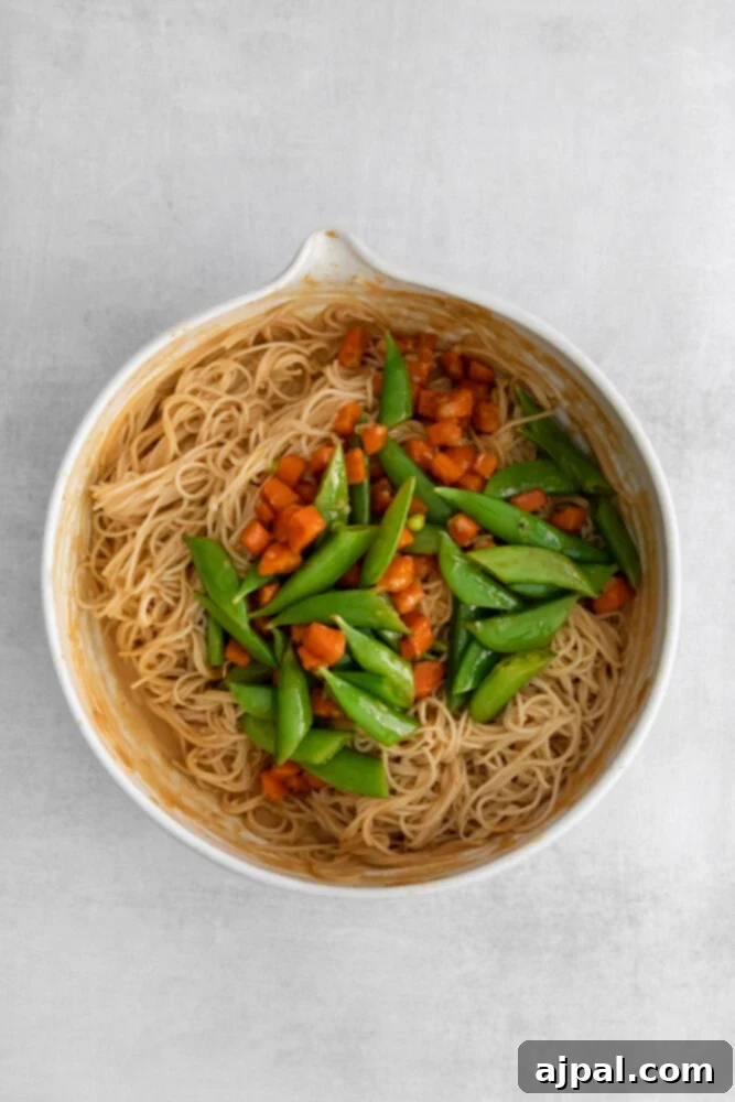 Kickin' Peanut Noodles 8 Vibrant snap peas and thinly sliced carrots are added to a bowl of noodles already coated in a rich peanut sauce, enhancing color and crunch.