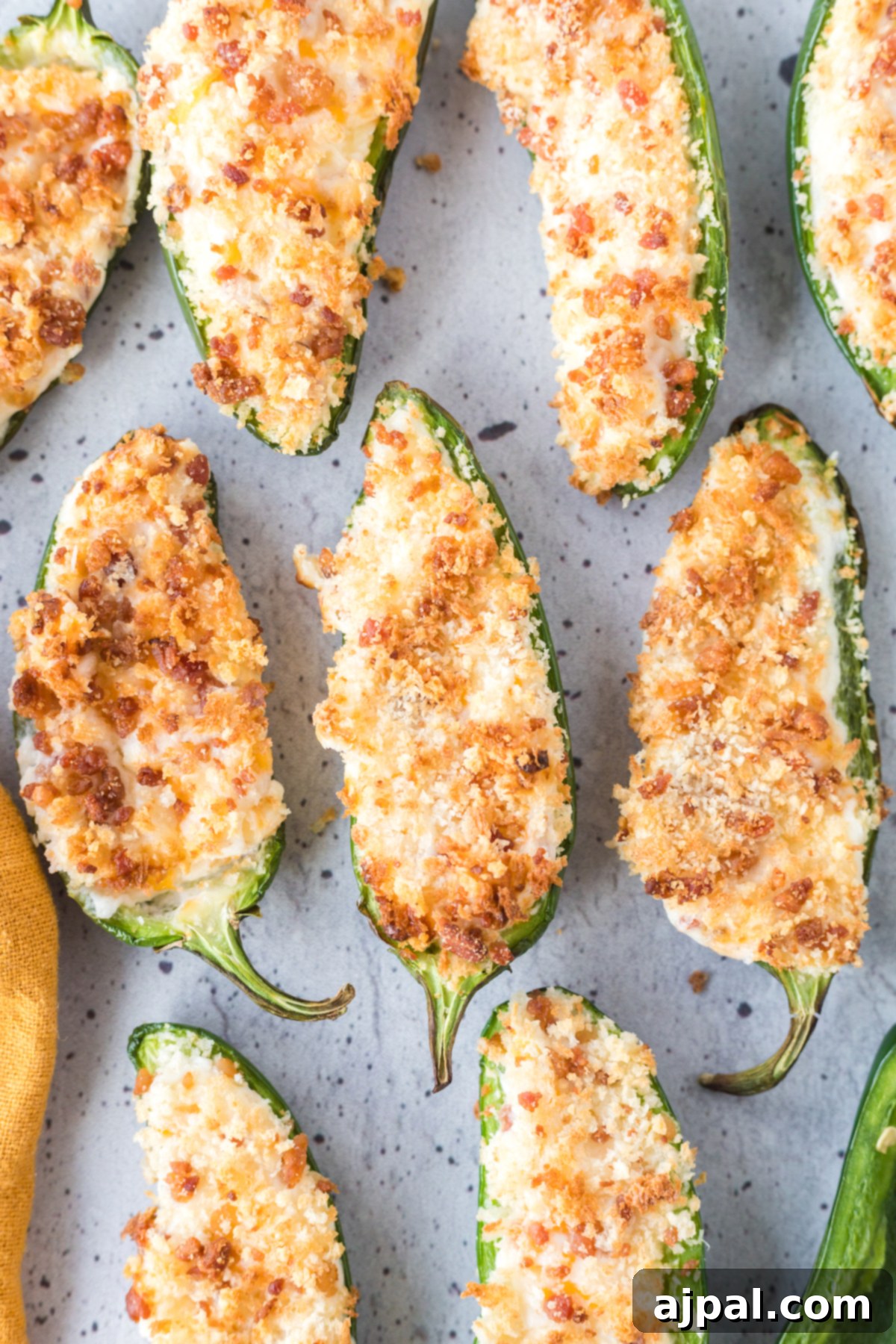 A selection of air-fried jalapeño poppers, perfectly browned and crispy, with their creamy filling and panko topping, arranged on a pristine white plate.