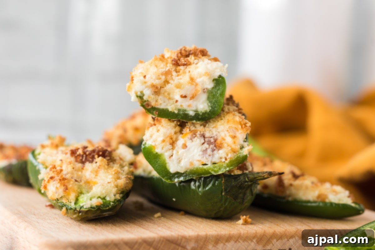 A stack of air-fried jalapeño peppers, each expertly sliced in half and filled with a creamy cheese blend, topped with crispy breadcrumbs.